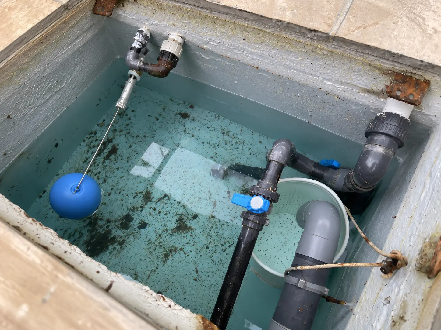 Open balancing tank in a pool plant room, with a float valve on the inlet pipe