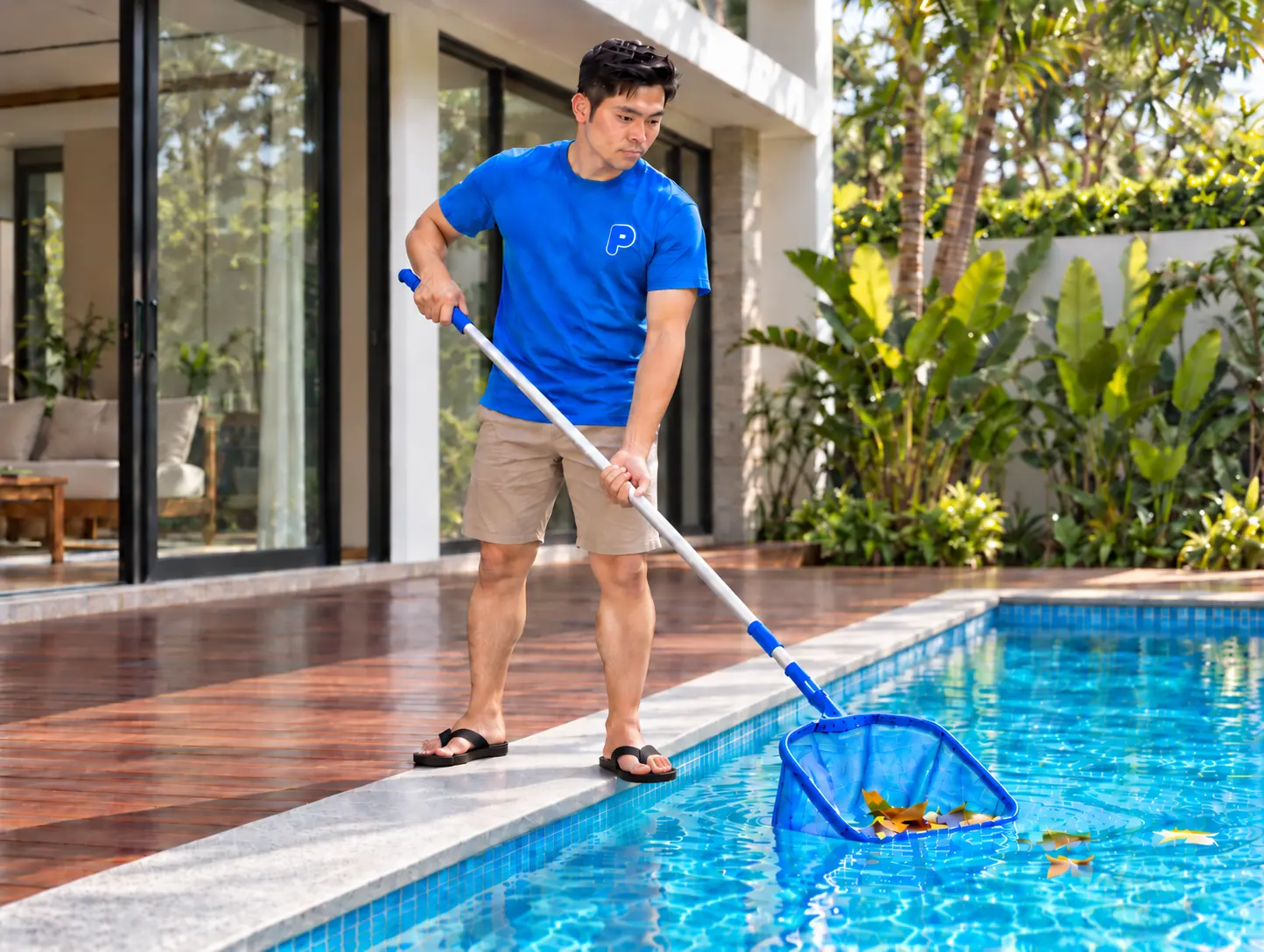 Pool technician skimming leaves from a landed home pool