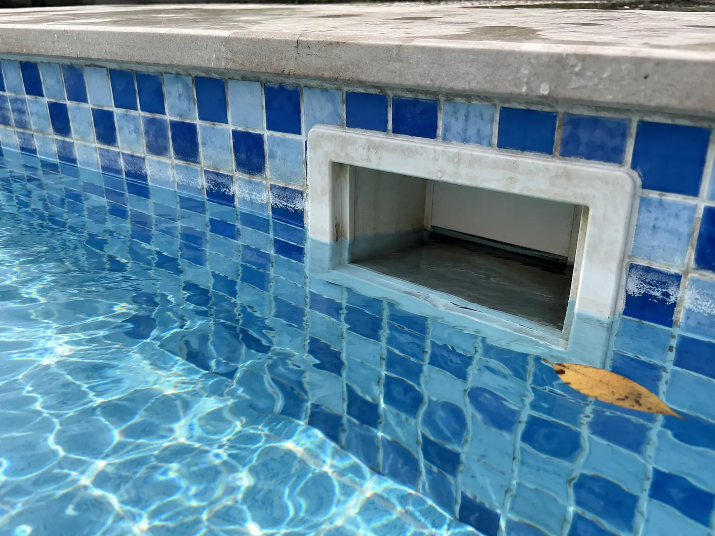 Pool water level below its usual line at the skimmer, with a mark on the tiles